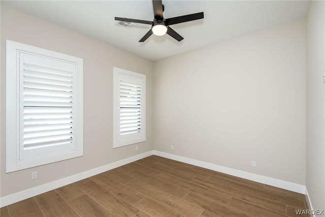 spare room with ceiling fan, visible vents, baseboards, and wood finished floors