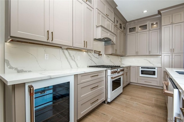 kitchen featuring wine cooler, decorative backsplash, glass insert cabinets, light stone countertops, and white appliances