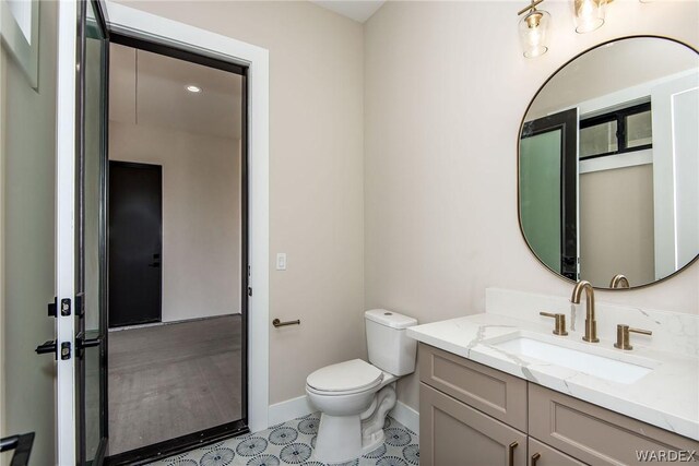 bathroom with toilet, baseboards, and vanity