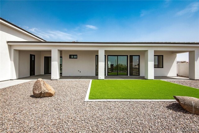 back of property featuring a yard and stucco siding