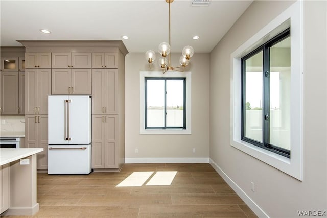 kitchen featuring high end white refrigerator, light wood finished floors, baseboards, hanging light fixtures, and recessed lighting