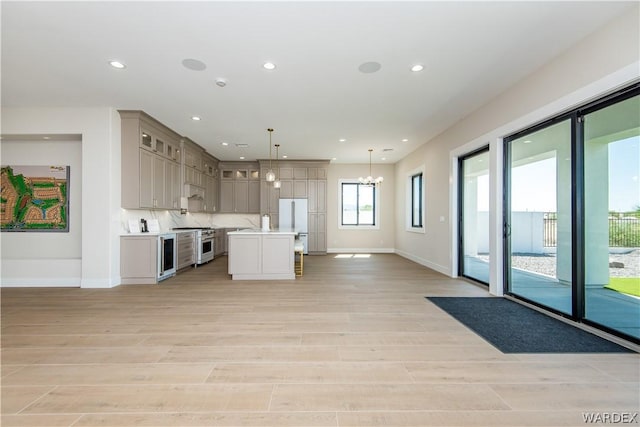 kitchen with stainless steel stove, a kitchen island, light countertops, gray cabinets, and decorative light fixtures