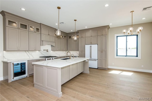 kitchen featuring a kitchen island with sink, wine cooler, high end white refrigerator, and glass insert cabinets