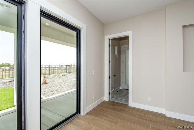 doorway to outside with visible vents, plenty of natural light, light wood-style flooring, and baseboards