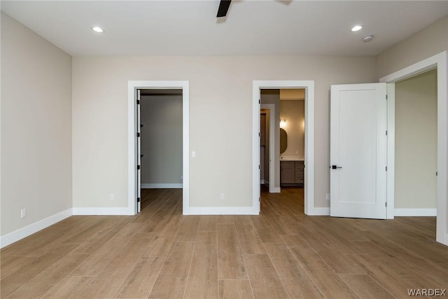 unfurnished bedroom featuring light wood-type flooring, baseboards, and a walk in closet