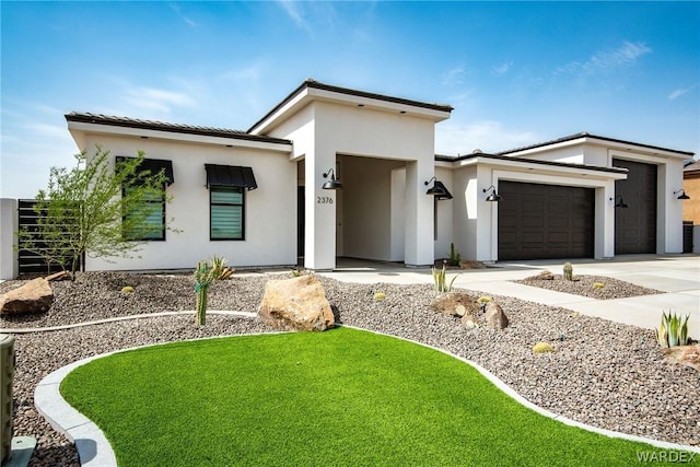 modern home featuring concrete driveway, a front lawn, an attached garage, and stucco siding