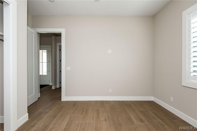 spare room with baseboards and wood finished floors