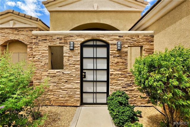 entrance to property with stone siding and stucco siding