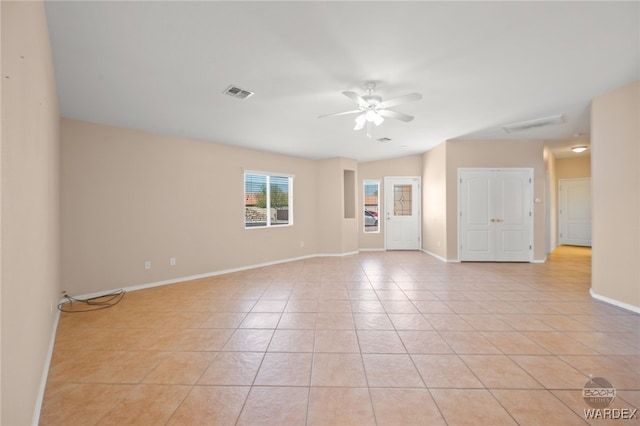 empty room with a ceiling fan, visible vents, baseboards, and light tile patterned floors