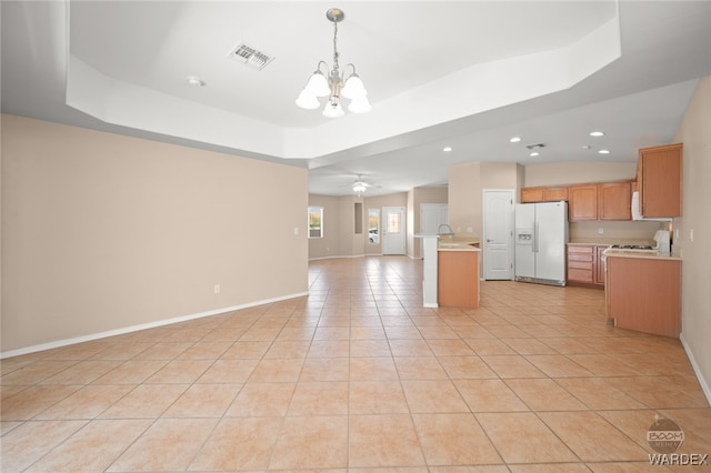 kitchen with a tray ceiling, visible vents, light countertops, open floor plan, and white fridge with ice dispenser