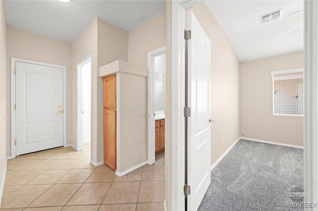 hallway featuring visible vents, baseboards, and light tile patterned floors