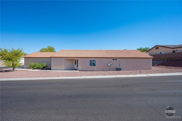 view of front of house featuring central air condition unit, a tiled roof, and stucco siding