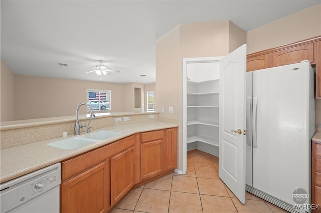 kitchen with light tile patterned floors, white appliances, a sink, visible vents, and light countertops