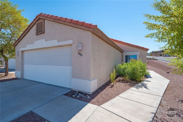 view of home's exterior with a garage, concrete driveway, a tile roof, an outdoor structure, and stucco siding