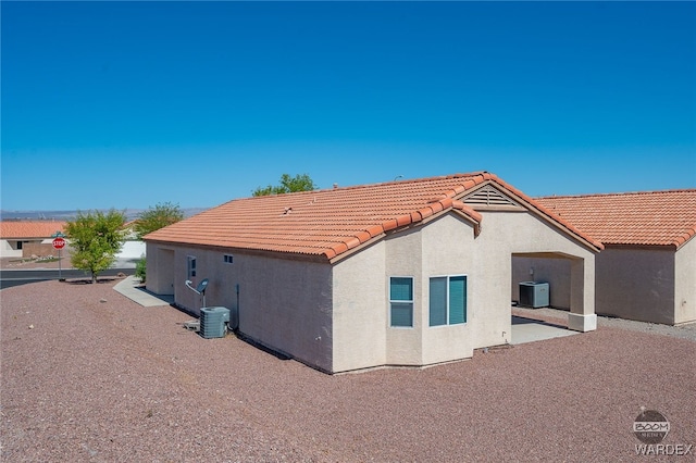 rear view of property featuring a patio area, a tile roof, central AC unit, and stucco siding