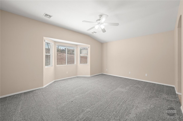 carpeted spare room featuring ceiling fan, visible vents, baseboards, and vaulted ceiling