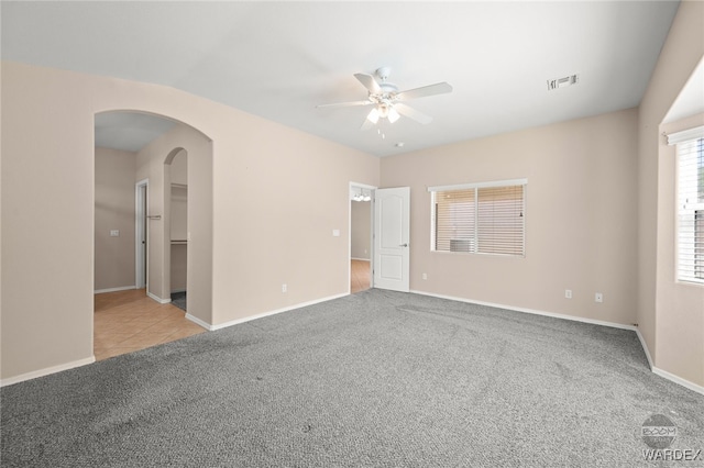 unfurnished room with ceiling fan, carpet, visible vents, and arched walkways