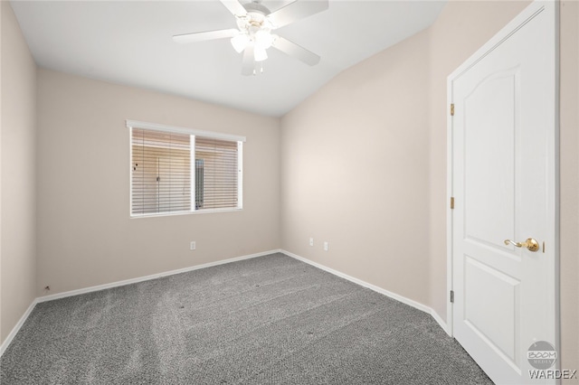 carpeted spare room with baseboards, vaulted ceiling, and a ceiling fan