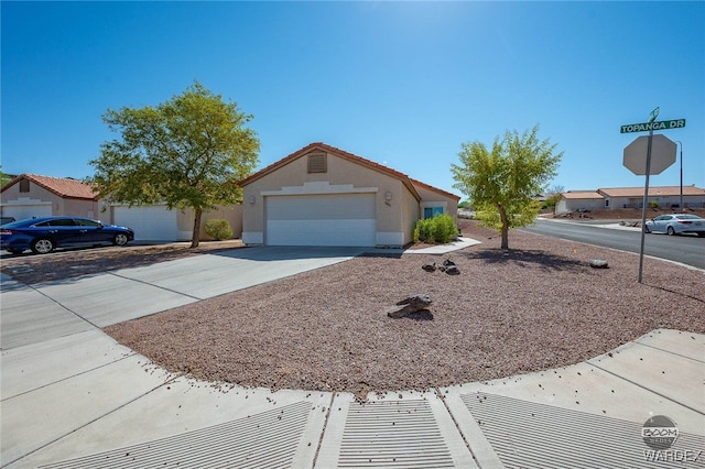 single story home with a garage, driveway, a tiled roof, and stucco siding