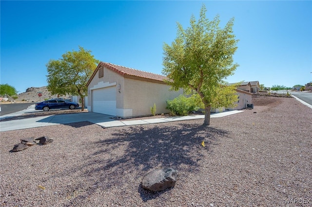 2460 Topanga Dr, Bullhead City, AZ 86442 - view of side of home with a tiled roof, an attached garage, driveway, and stucco siding