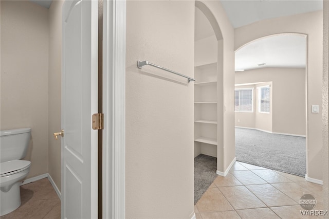 bathroom with baseboards, toilet, and tile patterned floors