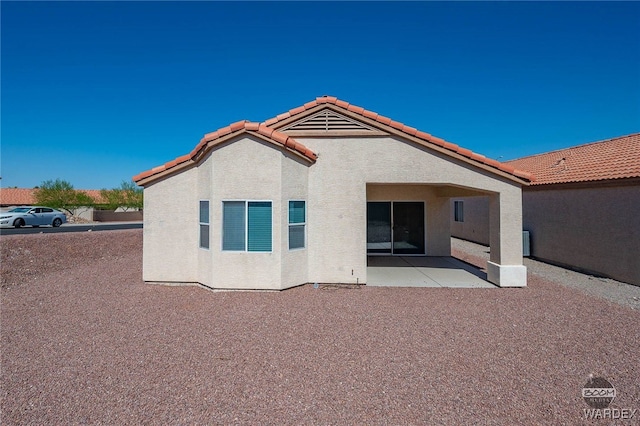 back of house with a patio area, a tile roof, and stucco siding