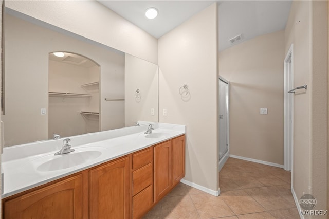 bathroom featuring double vanity, visible vents, a stall shower, a sink, and tile patterned flooring