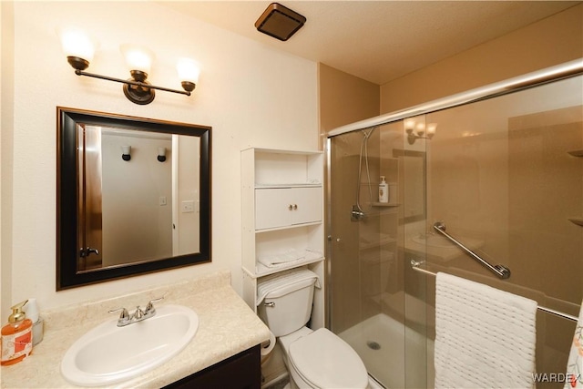 bathroom featuring toilet, a shower stall, and vanity