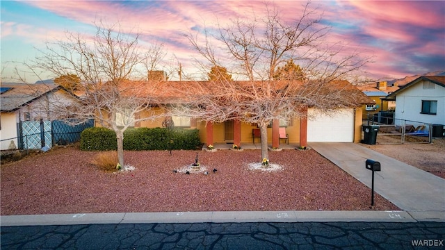 single story home with concrete driveway, fence, and an attached garage