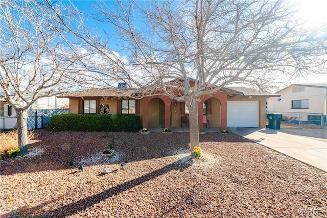 view of front of house featuring a garage, stucco siding, driveway, and fence