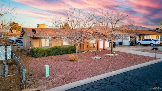 single story home with stucco siding, driveway, an attached garage, and fence