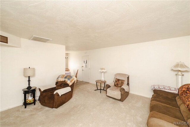 living area featuring visible vents, a textured ceiling, and light colored carpet