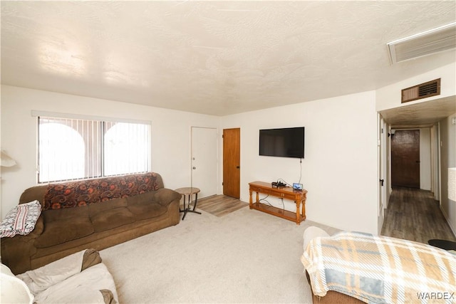 carpeted living room featuring visible vents and a textured ceiling