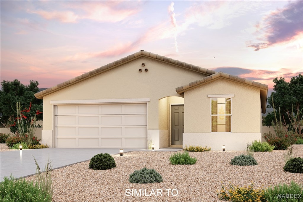 view of front of home with stucco siding, a tiled roof, concrete driveway, and a garage