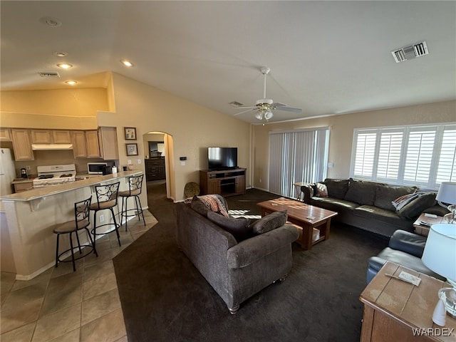 living area with arched walkways, tile patterned flooring, visible vents, and lofted ceiling