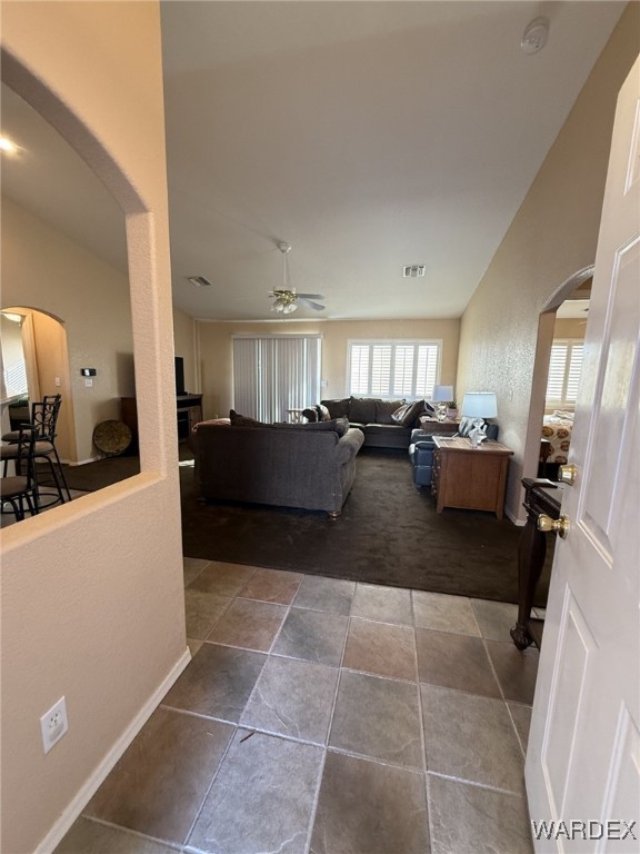 living room featuring a ceiling fan, arched walkways, and baseboards