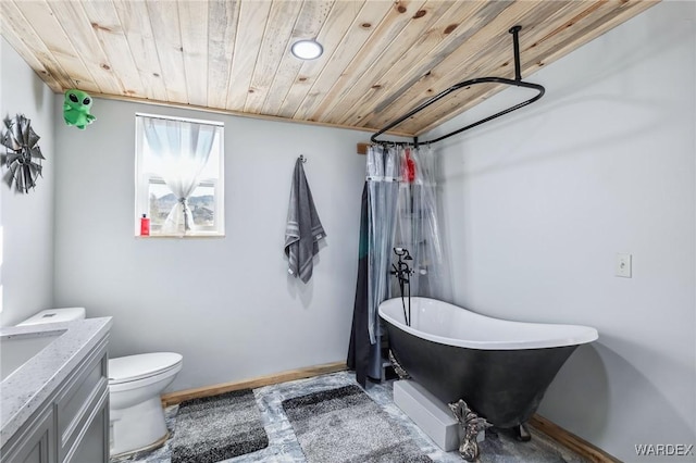 bathroom with baseboards, toilet, wooden ceiling, vanity, and a freestanding tub