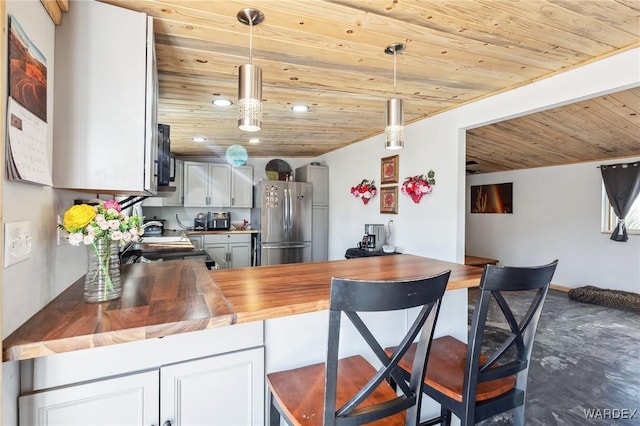 kitchen featuring wooden ceiling, freestanding refrigerator, pendant lighting, wooden counters, and recessed lighting