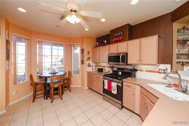 kitchen featuring stainless steel appliances, recessed lighting, light countertops, light tile patterned flooring, and a sink