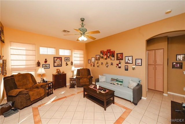 living room featuring light tile patterned floors, visible vents, arched walkways, baseboards, and ceiling fan