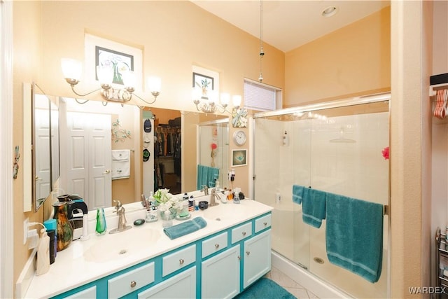 bathroom with a sink, double vanity, a walk in closet, and a shower stall