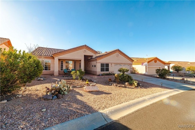 mediterranean / spanish home featuring a garage, concrete driveway, a tiled roof, and stucco siding