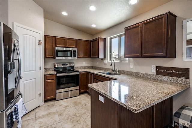 kitchen with appliances with stainless steel finishes, recessed lighting, a peninsula, lofted ceiling, and a sink