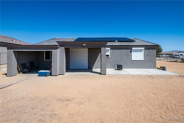 back of house with a patio area, solar panels, and stucco siding