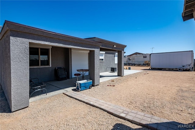 rear view of house with a patio area, an outdoor structure, a storage unit, and stucco siding
