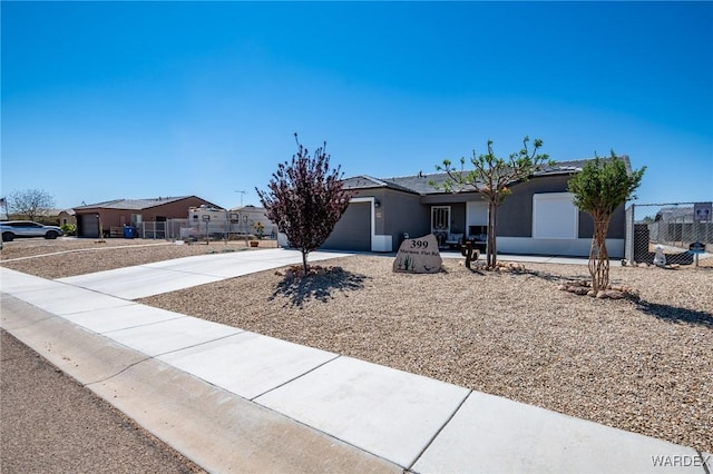 ranch-style house with driveway, stucco siding, fence, and an attached garage