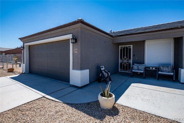 view of front facade with driveway, a garage, stucco siding, and fence