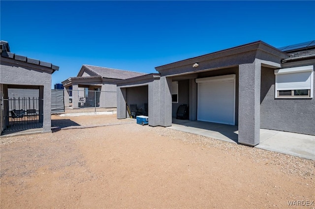 rear view of house featuring stucco siding and fence