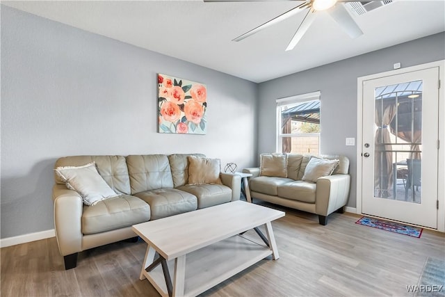 living area featuring visible vents, ceiling fan, baseboards, and wood finished floors