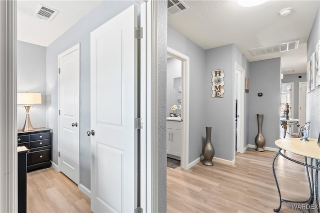 corridor with light wood-style floors and visible vents